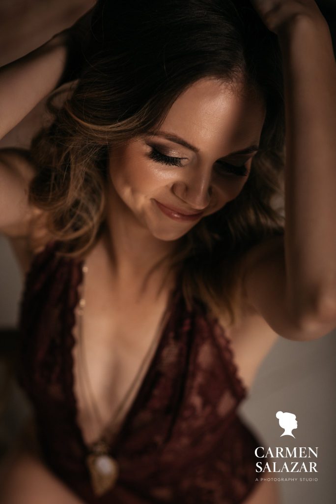 Woman deep burgundy lingerie with pale background; The Best Time To Book Your Boudoir Session; boudoir photography by Carmen Salazar